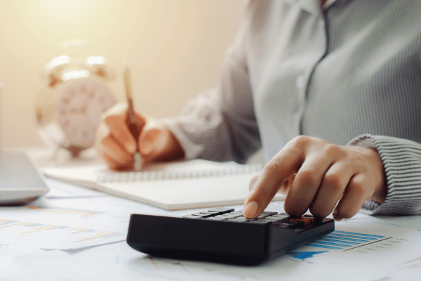 A person uses a calculator and takes notes while planning for tax deductions.